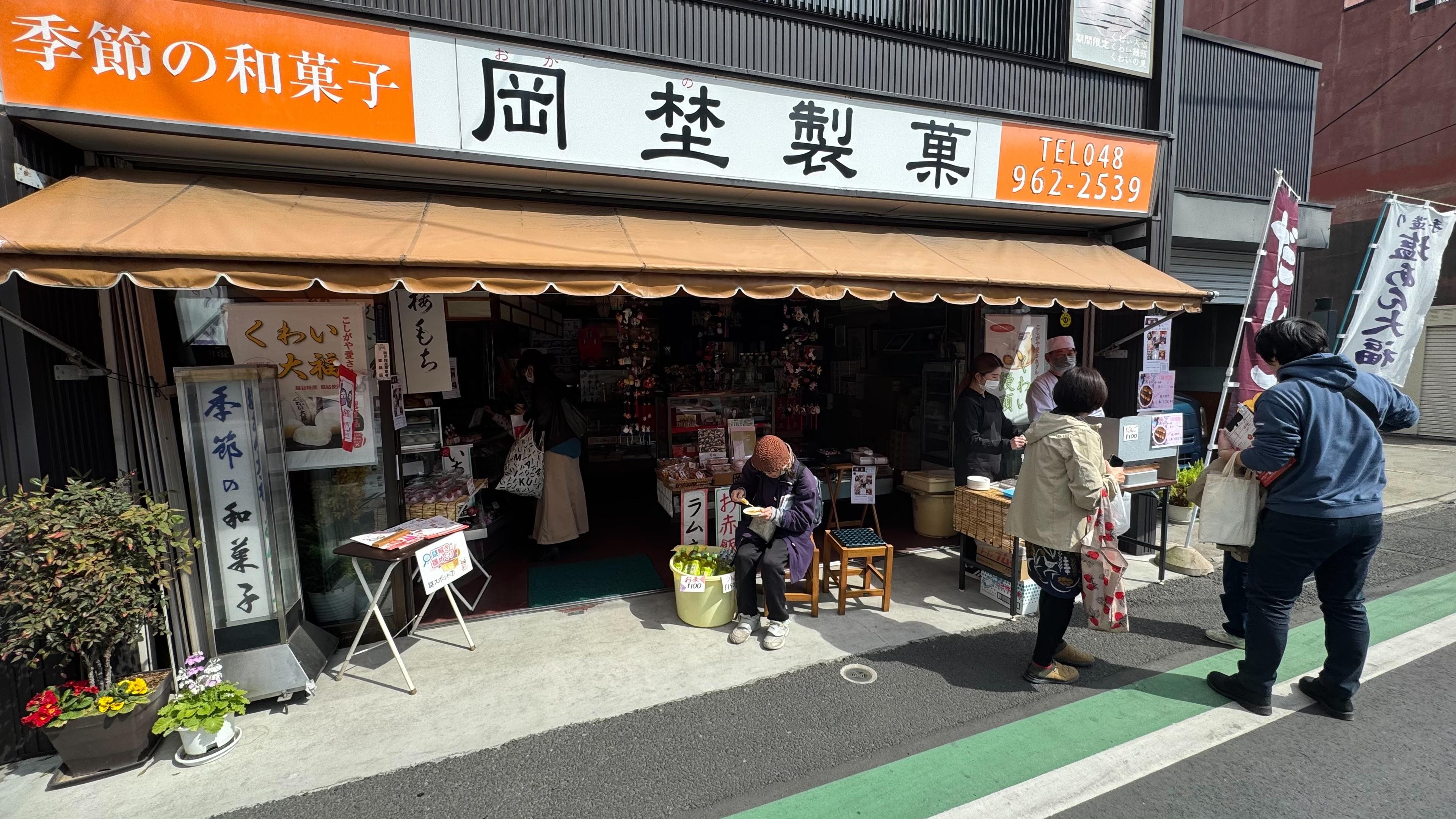 「季節の和菓子」の看板を掲げた岡埜製菓店の店先。テントの下に季節の和菓子が並ぶ